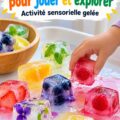Un enfant s'amusant avec des glaçons comestibles colorés dans une boîte, explorant différents sens.